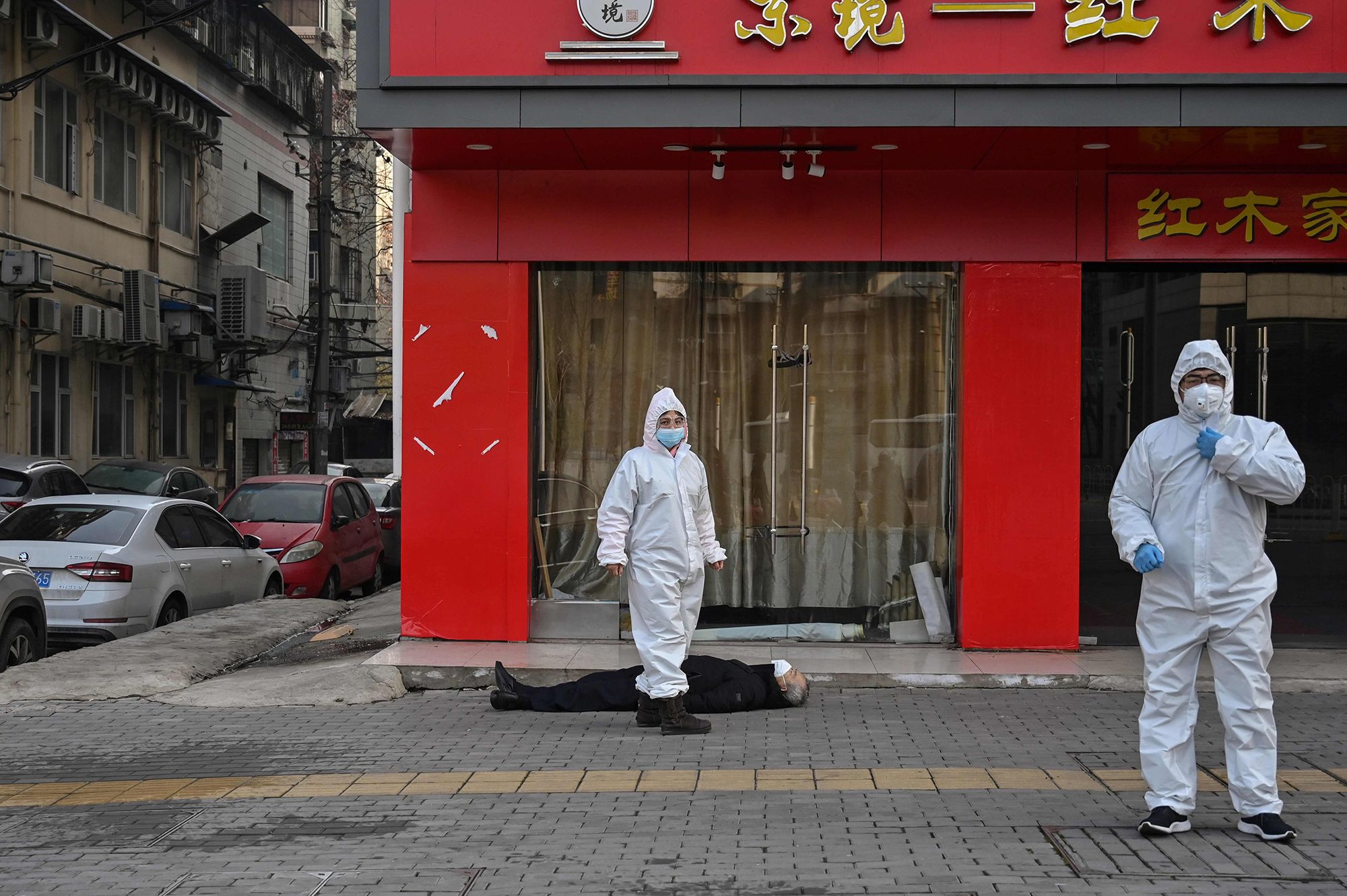 Officials stand near on elderly man who collapsed and died on a street near a hospital in Wuhan, China, on Jan. 30, 2020.